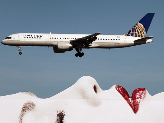 A United Airlines Boeing 757 passes a billboard on