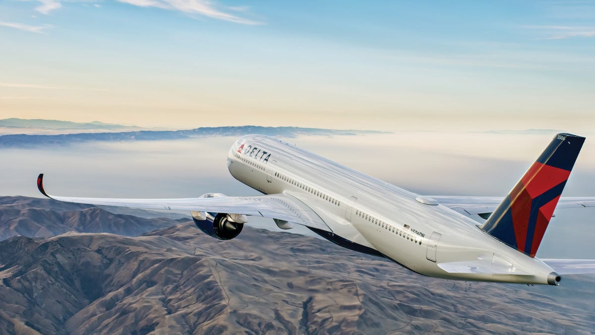 A Delta Air Lines Airbus A350 flying over mountainous terrain.