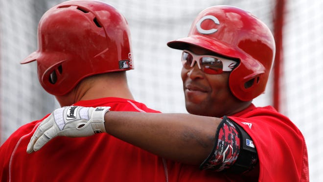 Reds outfielder Marlon Byrd hugs first baseman Joey Votto during batting practice at spring training.