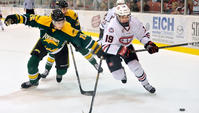 St. Cloud State's Mikey Eyssimont, right, beats University of Regina's Carter Hansen to the puck in the corner behind Regina's goal in the first period Sunday, Oct. 2, at Herb Brooks National Hockey Center.