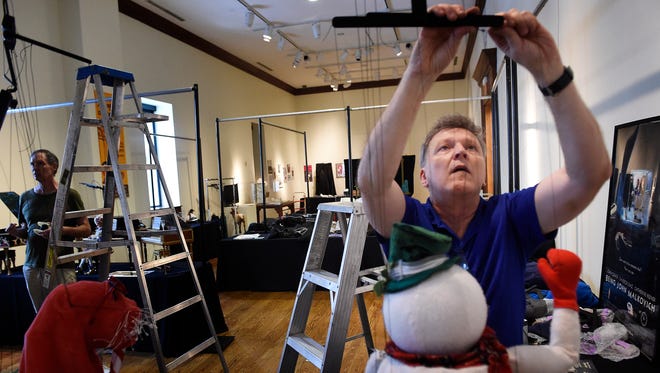 Emmy Award-winning puppeteer Phillip Huber hangs up one of a number of his marionettes that will be displayed at the Nashville International Puppet Festival at the downtown library this weekend.