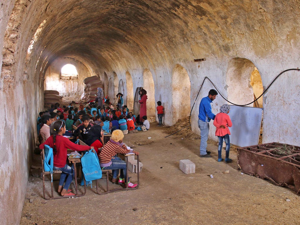 A Syrian girl practices basic arithmetic with a teacher during class in a barn that has been converted into a makeshift school to teach internally displaced children from areas under government control, in a rebel-held area of Daraa, in southern Syri