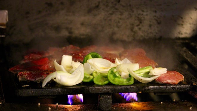 Onions and peppers sizzle on the grill next to filet mignon at Braseiro restaurant near  Copacabana beach in Rio de Janeiro.