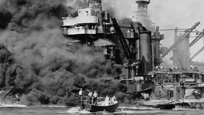 In this photo from Dec. 7, 1941, a small boat rescues a seaman from the burning USS West Virginia in Pearl Harbor, Hawaii, after Japanese aircraft attacked the military installation. More than 2,300 U.S. service members and civilians were killed in the strike that brought the United States into World War II.
