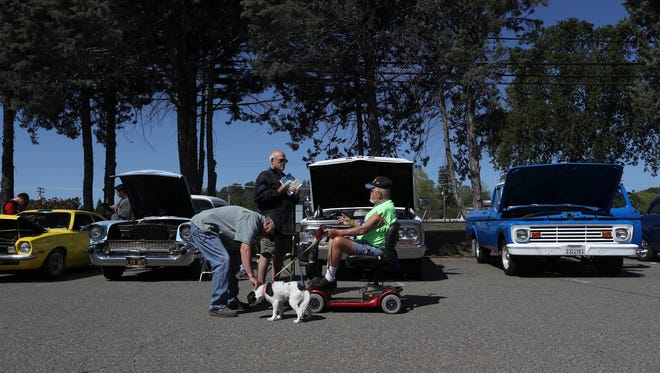 Glenn Smith, from left, Wayne Osborne, Thomas Parker, and his dog Winnie the Pooh have a chat while looking at cars Monday at the ROP Automotive Tech Program.