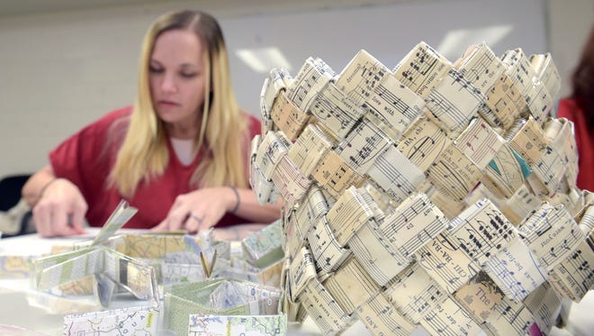 Angela Moore folds maps to be weaved into making a handbag inside the Davidson County jail on Thursday, Dec. 8, 2016.  The handbags are part of  a nonprofit social enterprise program called Dreanweave that pays women in Davidson County  jail who weave handbags out of magazines, maps, other paper.   One of the goal of the program is to women a chance to learn a skill and actually make money.