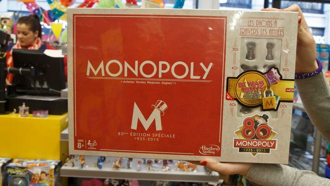 A saleswoman displays the new Monopoly board game version at a toy store near the Champs Elysees avenue in Paris, Wednesday, Feb. 4, 2015. The French version of Monopoly is celebrating its 80th year by slipping cash into 80 boxes of the game. One box will have the full complement in real money  20,580 euros ($23,600) as well as the Monopoly money needed to actually play the game, one of the most popular in France. 79 other boxes will have smaller amounts according to Hasbro. (AP Photo/Michel Euler)