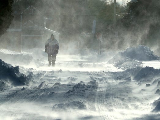 A pedestrian walks through blowing snow along Stites