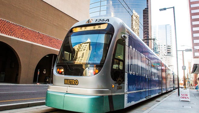 A light rail train pulls out of the station heading north on Central Avenue just north of Adams Street in downtown Phoenix.