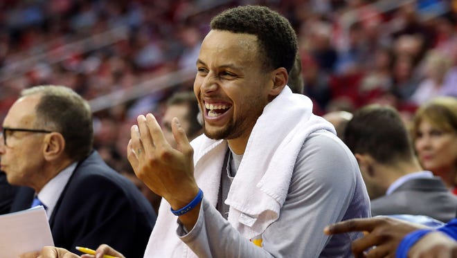 Stephen Curry (30) smiles from the bench during the second quarter against the Houston Rockets at Toyota Center.