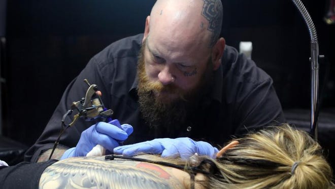 Lauryn Williams gets a tattoo from Tony Hundahl of Rock of Ages Tattooing in Austin, Texas, on Sunday during the Ink & Iron festival at Municipal Auditorium.