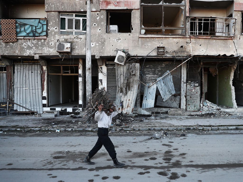 A Syrian man carries wood to be used for heating in the rebel-held town of Douma, Syria, on the eastern outskirts of Damascus on Jan. 3, 2017.
