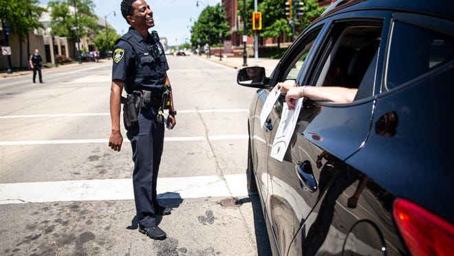 Springfield Police Officer Lamar Moore is greeted by people as he helps direct cars into the line for the Solidarity Vehicle Procession hosted by Black Lives Matters Springfield on May 31.
