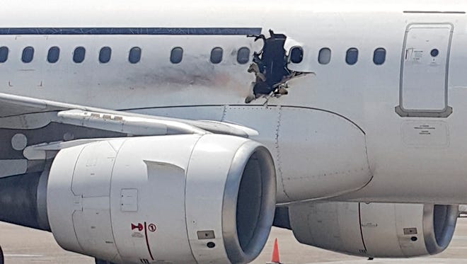 In this Tuesday, Feb. 2, 2016 photo, a hole is photographed in a plane operated by Daallo Airlines as it sits on the runway of the airport in Mogadishu, Somalia. A gaping hole in the commercial airliner forced it to make an emergency landing at Mogadishu's international airport late Tuesday, officials and witnesses said. (AP Photo)