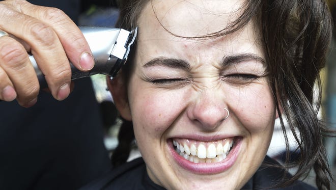 Sarah Stirling reacts to the first few strokes from the clipper during Baldrick's Foundation's head shaving event to raise funds for childhood cancer research Friday, May 8, 2015, on Colorado State University's campus in Fort Collins, CO.