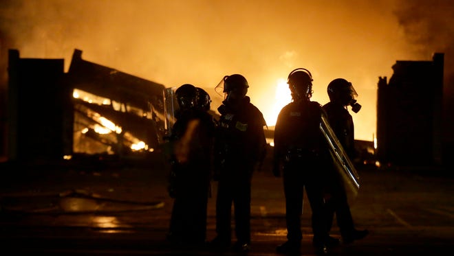 Police officers watch the neighborhood as some buildings are set on fire Monday night.