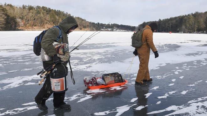 Chris Fidler, left, of Halifax, and Ben Reigert, of Reading, walk out onto the ice at Sweet Arrow Lake, to fish on Saturday, Jan. 6, 2018, in Pine Grove, Pa. Freezing temperatures since December 26 have made for ideal ice fishing conditions. (David McKeown/Republican-Herald via AP)