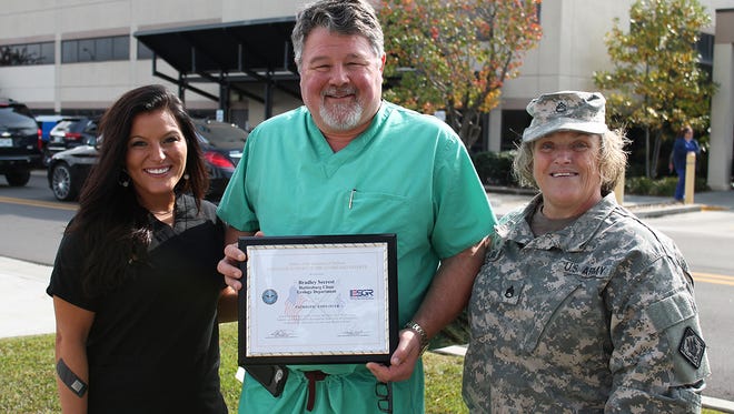 Pictured from left are Alisha Maxcey, administrative LPN for Dr. Secrest; Hattiesburg Clinic Urologist Bradley N. Secrest, MD; and Staff Sgt. September Wallace. Staff Sgt. Wallace presented Dr. Secrest with the Patriot Award for his support of Maxcey, who is an Army National Guard sergeant, while she was deployed.