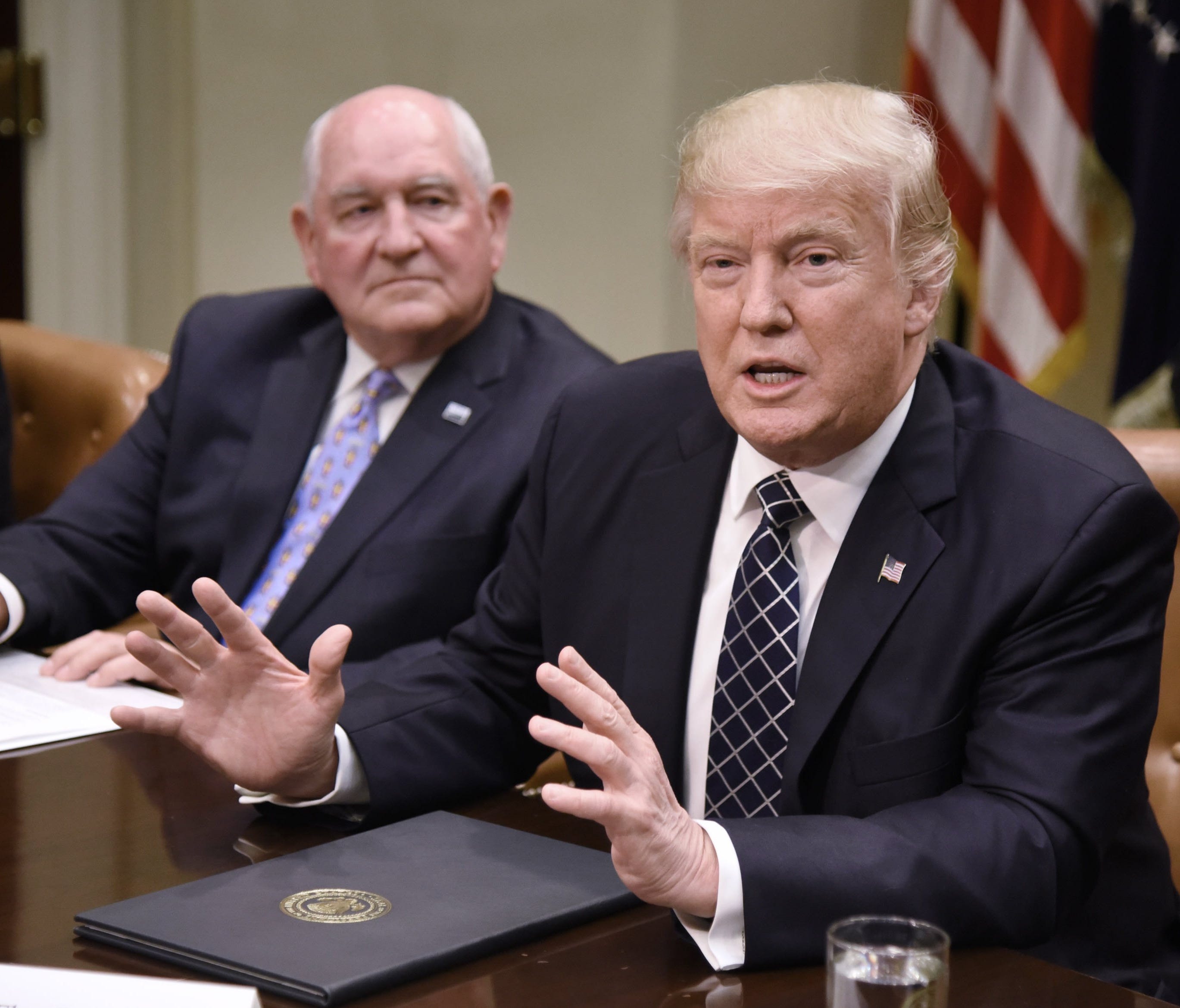 President Donald Trump speaks as Secretary of Agriculture Sonny Perdue looks on after signing the Executive Order Promoting Agriculture and Rural Prosperity in America during a roundtable with farmers in the Roosevelt Room of the White House in Washi