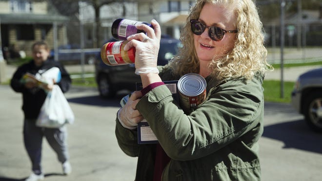 Lynn Ehmen carries supplies to the micro food pantry at Lanphier High School as Kristina Moss arrives to drop off supplies, too, Saturday, April 18, 2020. The micropantries operate on a "leave what you can, take what you need" premise.