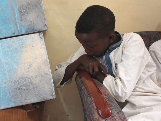 12-year-old Abdelqader looks down at his side as he