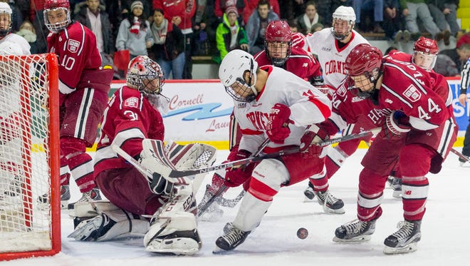 Harvard goalie Merrick Madsen watches the puck as Cornell's Eric Freschi, center, and Harvard's Michael Floodstrand try to control it in the closing minutes of Cornell's 6-2 loss Saturday at Lynah Rink.