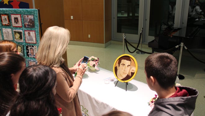 Friends and family admire a floral picture of Andrew Jova.