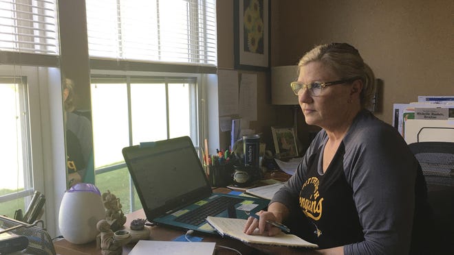 This April 3, 2020 photo shows realtor Michelle Bushée posing at her desk while working from her home in Pittsburgh, Pa. Bushee has always been an avid planner. Her weeks used to be very busy but now the entire month of April is empty. (Nick Bushée via AP)