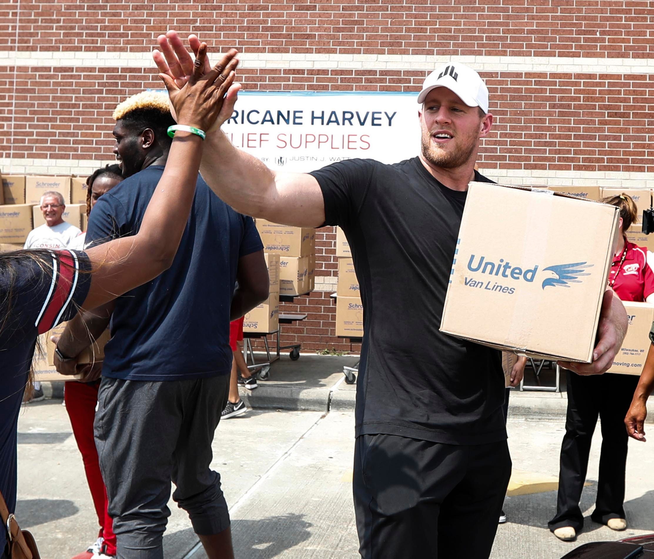 Anna Ucheomumu, left, high fives Houston Texans defensive end J.J. Watt after loading a car with relief supplies to people impacted by Hurricane Harvey on Sunday, Sept. 3, 2017, in Houston. J.J. Watt's Hurricane Harvey Relief Fund.