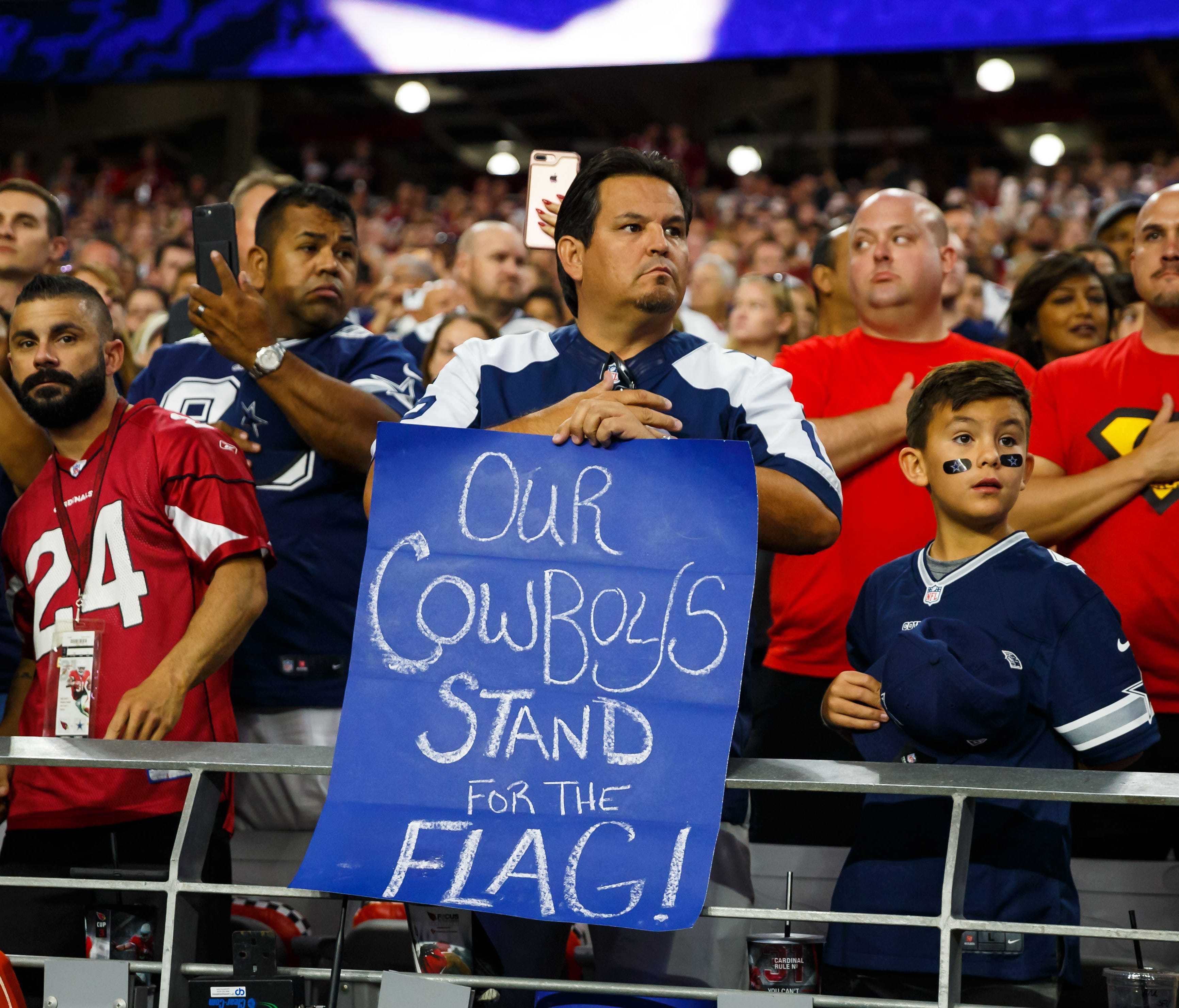 A Dallas Cowboys fan holds a sign as he stands during the national anthem prior to the game against the Arizona Cardinals at University of Phoenix Stadium.