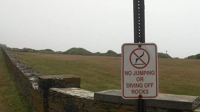 A sign warns people not to jump or dive off the rocks at 12 O'Clock High in Newport.