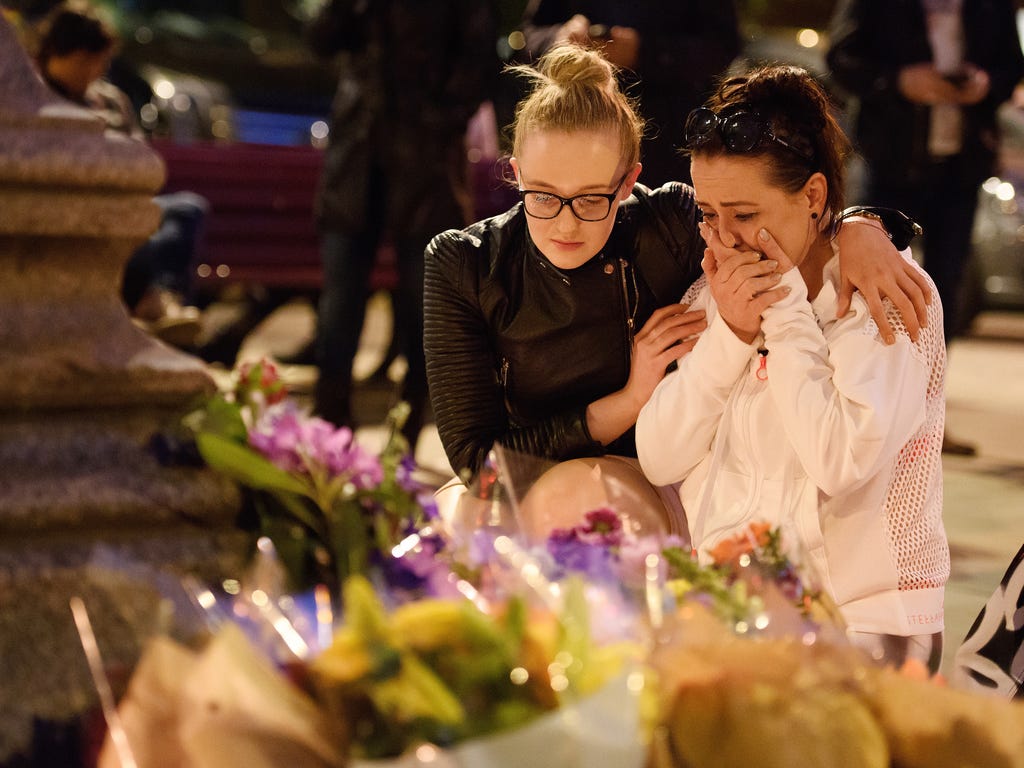 A woman is consoled as she looks at the floral tributes following an evening vigil outside the town hall  in Manchester, England. An explosion occurred at Manchester Arena as concert goers were leaving the venue after Ariana Grande had performed. Gre