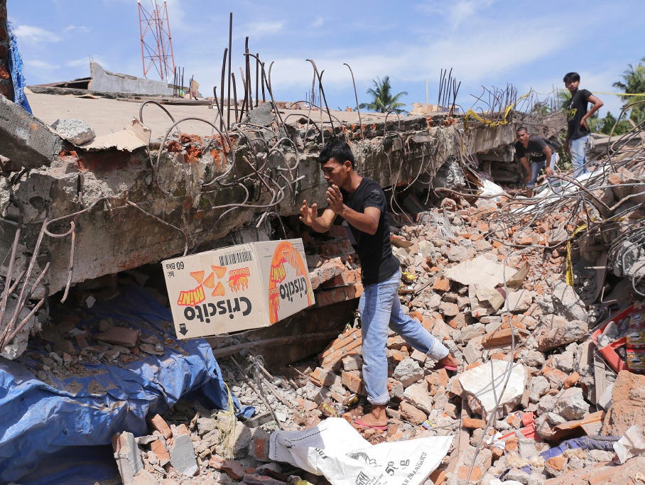 A man removes a box of food from under the rubble of a building that collapsed after an earthquake in Pidie Jaya, Aceh province, Indonesia, on Dec. 7.