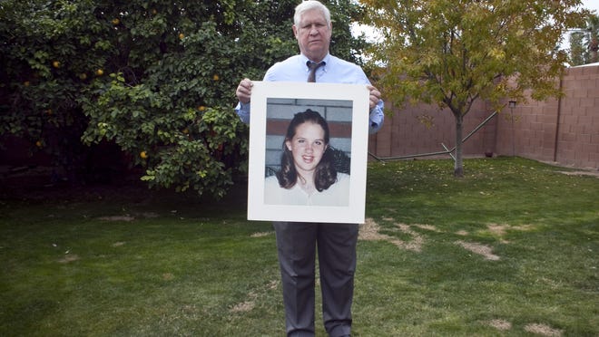 Otis Smith with a photo of his daughter, Shannon (taken in May,1999 when she was 14), in the backyard where she was shot.  Smith lost Shannon ten years ago to a bullet falling from the sky. Credit: Mark Henle/ The Arizona Republic