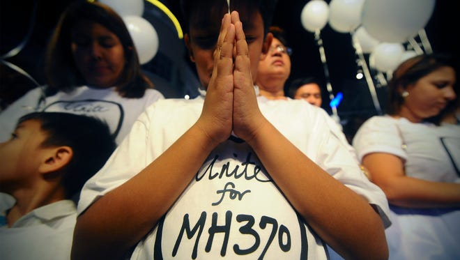 A young Malaysian boy prays at an event for the missing Malaysia Airlines Flight 370 in March 2014.