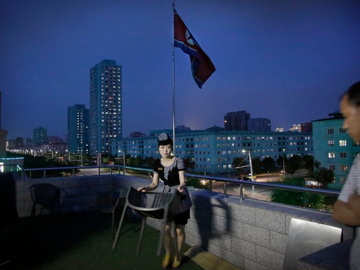 A waitress moves a dining chair at a restaurant terrace