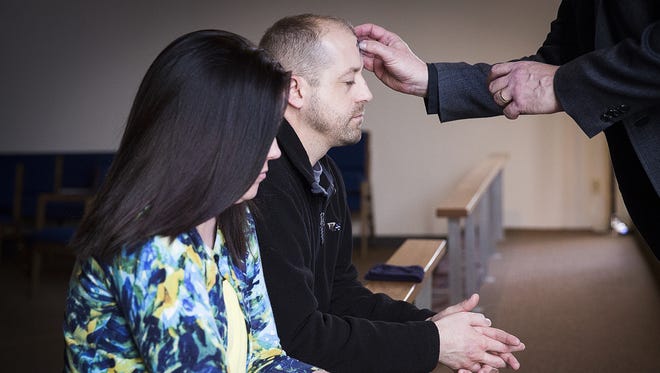 Church members Mark and Sherry Miller receive the imposition of ashes from the Rev. James M. Bischoff at Lutheran Church of the Cross on Ash Wednesday during an open afternoon service. Ash Wednesday is the start of Lent.