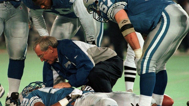 The Lions' Reggie Brown is attended by a trainer as Detroit's Antonio London (55) and Stephen Boyd (57) look on in the fourth quarter of their game against the New York Jets Sunday, Dec. 21, 1997, at the Silverdome in Pontiac.