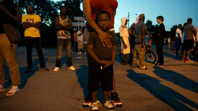 Jeremiah Parker, 4, stands in front of his mother, Shatara Parker, as they attend a protest Wednesday, Aug. 13, 2014, in Ferguson, Mo. Nights of unrest have vied with calls for calm in a St. Louis suburb where Michael Brown, an unarmed black teenager was killed by police, while the community is still pressing for answers about the weekend shooting. (AP Photo/Jeff Roberson)