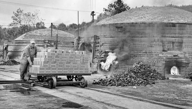 Clarence Watts pushes a load of dried bricks past of one of the kilns at the Medora Brick Co. in 1954. The "green" bricks will be put into a kiln and burned for five days to give them the red look.