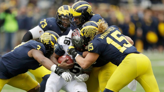 Ohio State quarterback J.T. Barrett (16) is sacked by Michigan defensive lineman Rashan Gary (3) and defensive lineman Chase Winovich (15) during the second half of an NCAA college football game, Saturday, Nov. 25, 2017, in Ann Arbor, Mich. Barrett did not return after the sack. (AP Photo/Carlos Osorio)