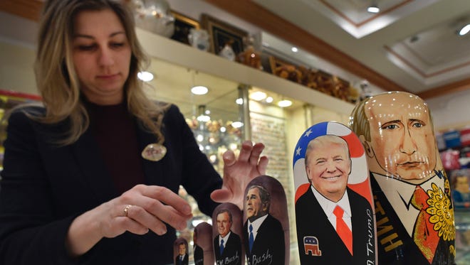 An employee displays traditional Russian wooden nesting dolls, Matryoshka dolls, depicting US President-elect Donald Trump, Russian President Vladimir Putin and other political leaders at a gift shop in central Moscow on Jan. 16, 2017,.