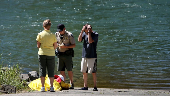 A friend and fellow paddle boarder, right, reacts to his friend drowning death after a trip to the Willamette River near Clearwater Park south east of Springfield, Ore., turned tragic Friday, June 19, 2015.