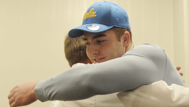 Oaks Christian's Bo Calvert is hugged by Lions head coach Jim Benkert during the Ventura County Football Coaches Association’s annual signing day luncheon at the Palm Garden Hotel in Newbury Park. Calvert is headed to UCLA.