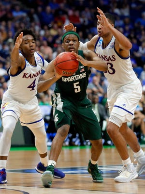 Kansas' Devonte' Graham (4) and Landen Lucas, force Michigan State' Cassius Winston (5) to pass the ball out in the first half of a second-round game in the men's NCAA college basketball tournament in Tulsa, Okla., Sunday, March 19, 2017. (AP Photo/Tony Gutierrez)