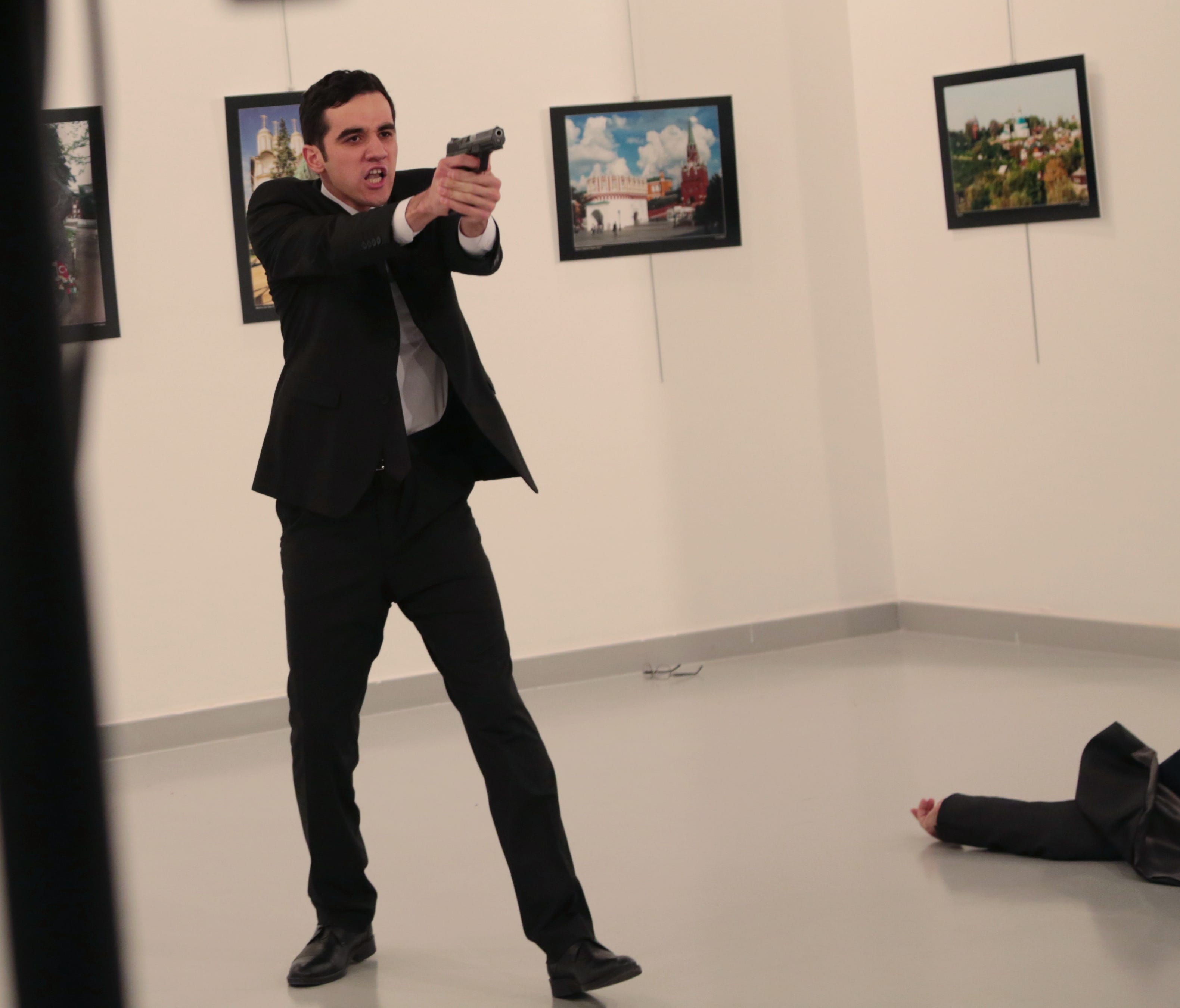 An unnamed gunman gestures after shooting the Russian Ambassador to Turkey, Andrei Karlov, at a photo gallery in Ankara, Turkey, Monday, Dec. 19, 2016. The Russian foreign ministry spokeswoman said he was hospitalized with a gunshot wound.