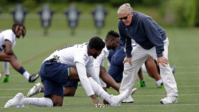 Seahawks coach Pete Carroll, right, greets Byron Maxwell during minicamp Tuesday in Renton. Maxwell, projected to be a starting defensive back, skipped optional workouts the previous two weeks, but showed up for this week's minicamp.