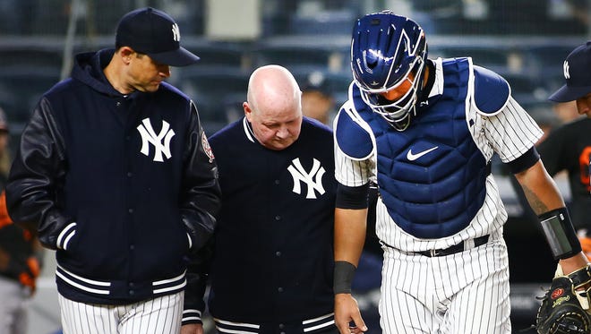 New York Yankees catcher Gary Sanchez (24) is helped off the field by trainer Steve Donahue after being injured as manager Aaron Boone (17) looks on against the Baltimore Orioles during the 14th inning at Yankee Stadium.