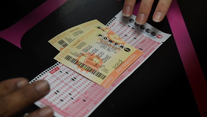 A customer picks up her California Powerball lottery tickets at the famous Bluebird Liquor store which is considered to be a lucky retailer of tickets, in Hawthorne, California on Jan. 13, 2016.