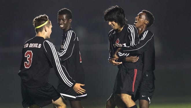 Green Bay East's Luis Ahumada gets a hug from teammate Mohamed Abdi, far right, after Ahumada's game-winning goal Tuesday against Seymour.